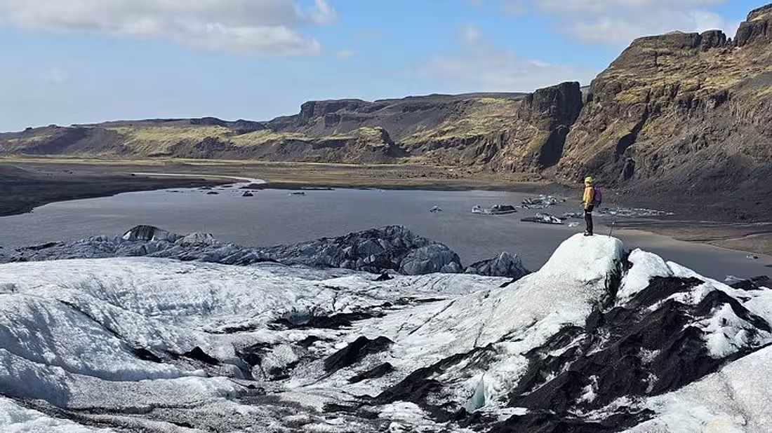 Lone person standing before a glacier lagoon