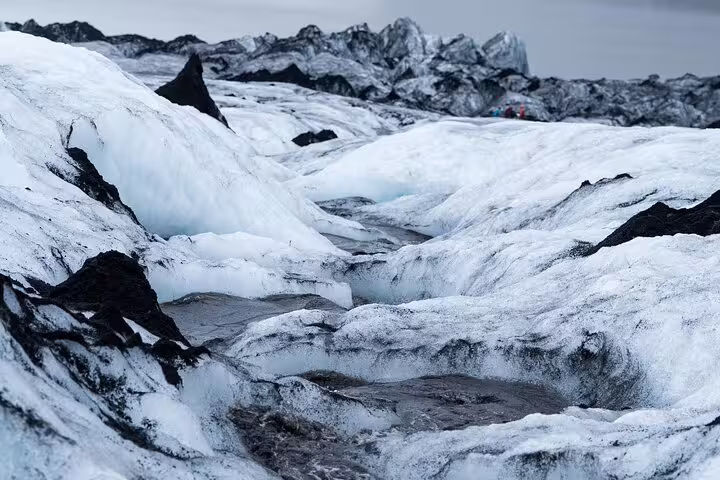 Rugged ice formations and crevasses on Sólheimajökull glacier with dark volcanic rock
