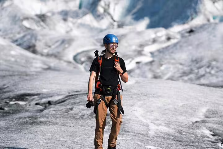 Solo hiker in helmet and harness trekking across vast Iceland glacier landscape on Glacier Lagoon adventure tour
