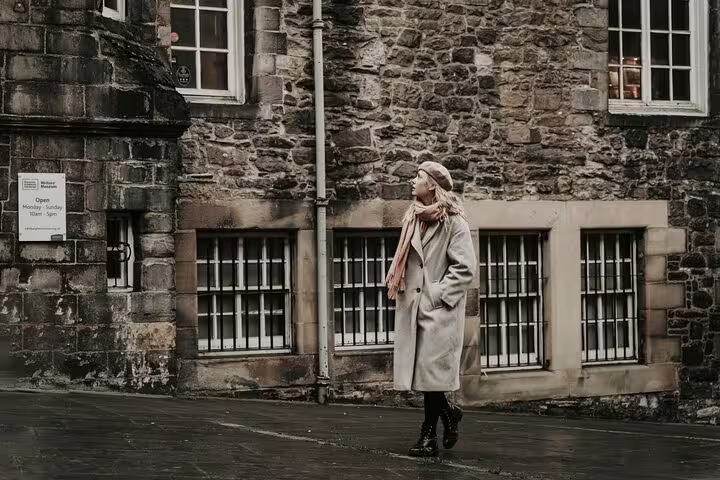 Solo traveler posing by historic stone buildings in Edinburgh Old Town on a private photoshoot with pro photographer