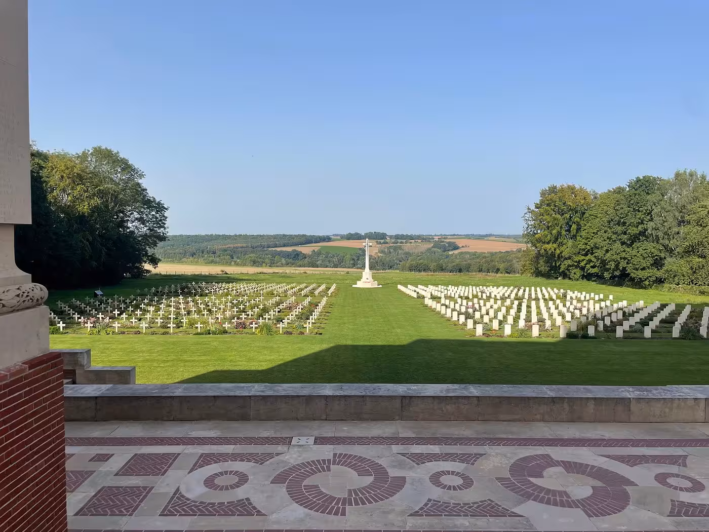 Somme battlefield cemetery with rows of white headstones and crosses overlooking French countryside