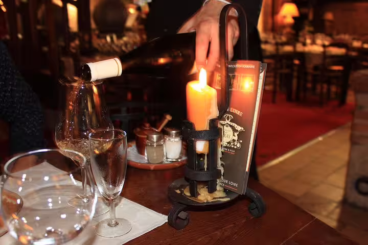 Sommelier pouring Loire Valley wine during tasting lunch, with candlelit table and glasses on the tour