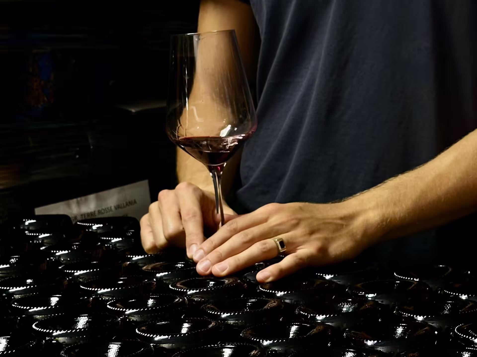Sommelier holding a glass of red wine in a Bologna winery cellar during boutique wine tasting with food platter