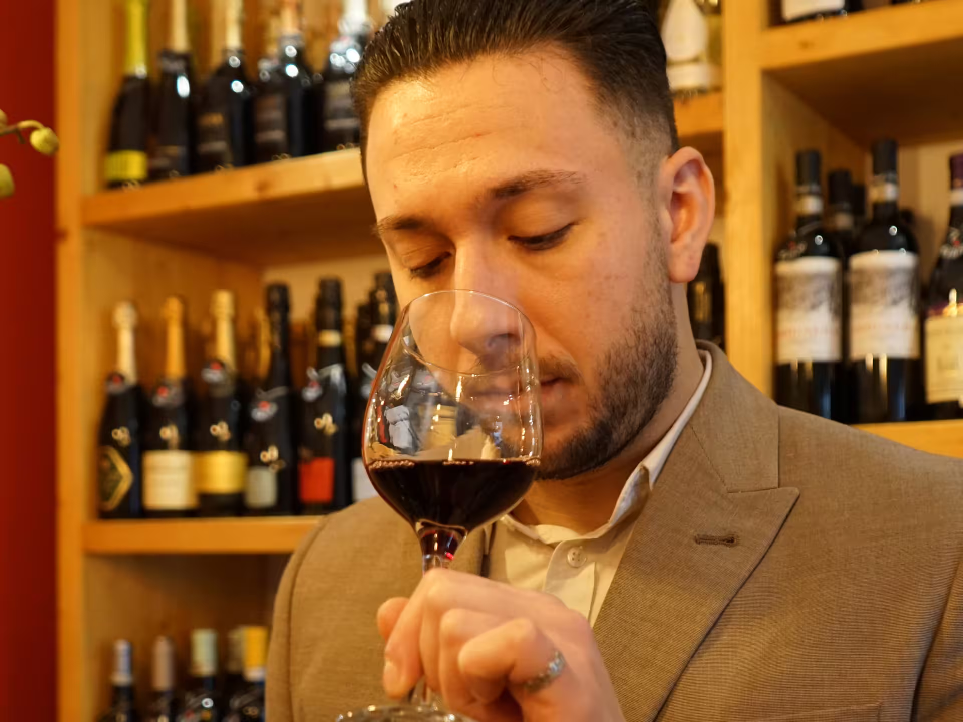 Sommelier-style host smelling a glass of red wine at a Turin city center wine tasting experience in a local enoteca