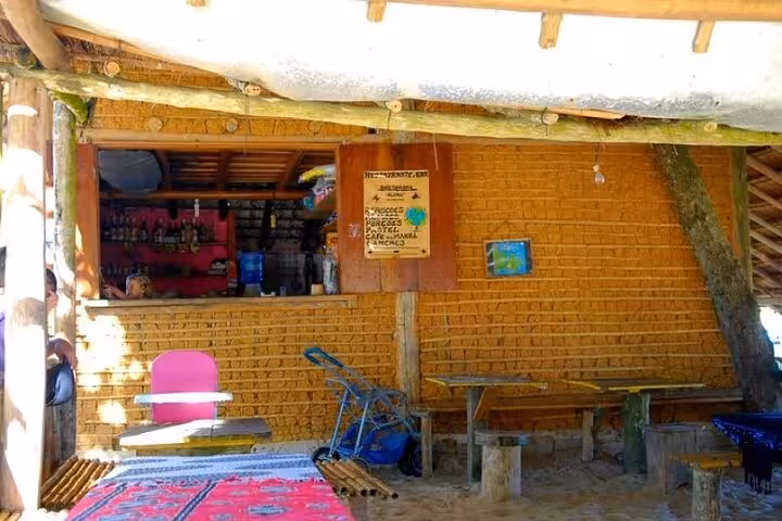 Rustic beachside cafe with wooden seating and colorful decor at Sono Beach, offering a cozy spot for refreshments.