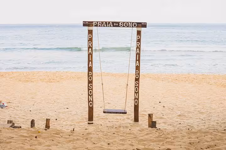 Rustic swing set on the sands of Sono Beach, offering a serene view of the ocean, perfect for relaxation and fun.
