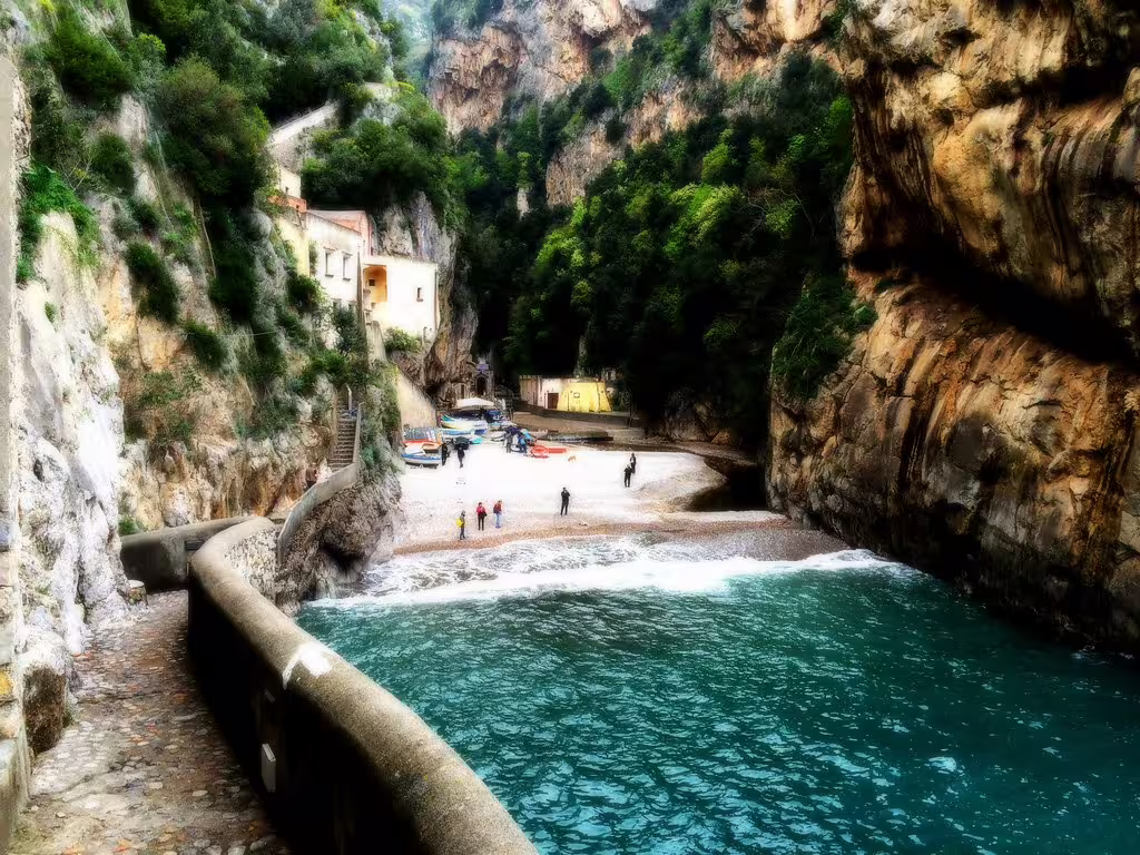 Hidden cove on the Amalfi Coast with turquoise sea, cliffside path and beach boats seen on a Sorrento coastal boat tour