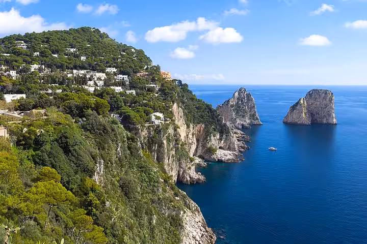 Stunning coastal view of Capri's cliffs and Faraglioni rocks during a private boat tour from Sorrento on a classic Gozzo.