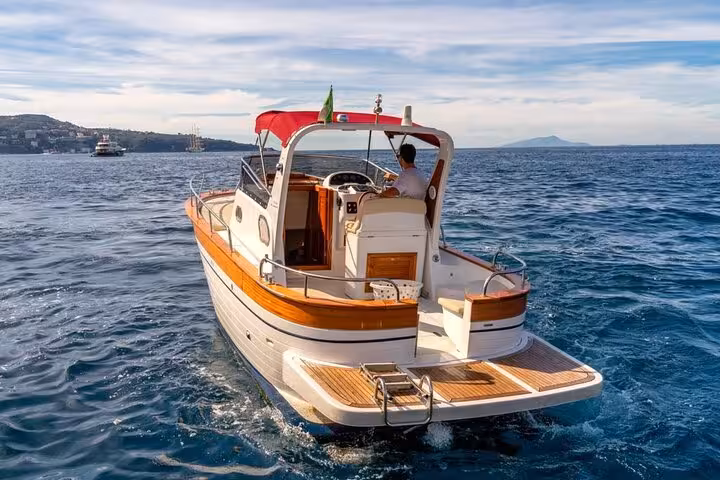 Enjoy a classic Gozzo boat ride from Sorrento to Capri, capturing the vibrant sea and coastal scenery.