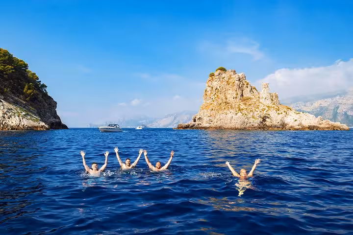 Group swimming near rocky island on Sorrento to Capri private boat tour, enjoying clear blue waters and scenic views.
