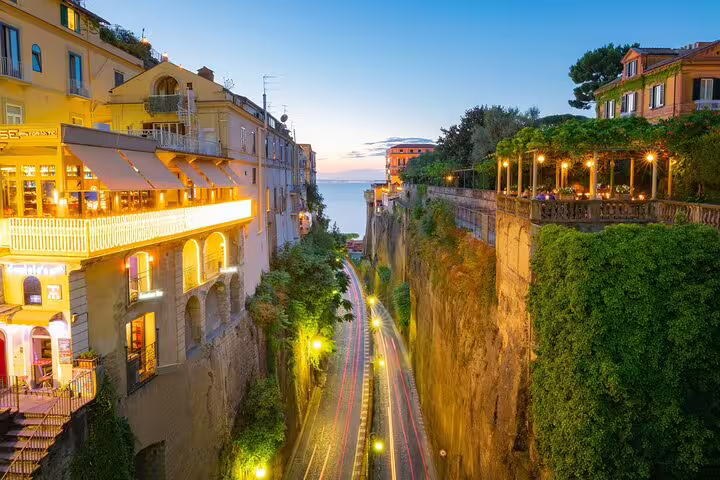 Illuminated cliffside streets of Sorrento at dusk with car light trails and sea view