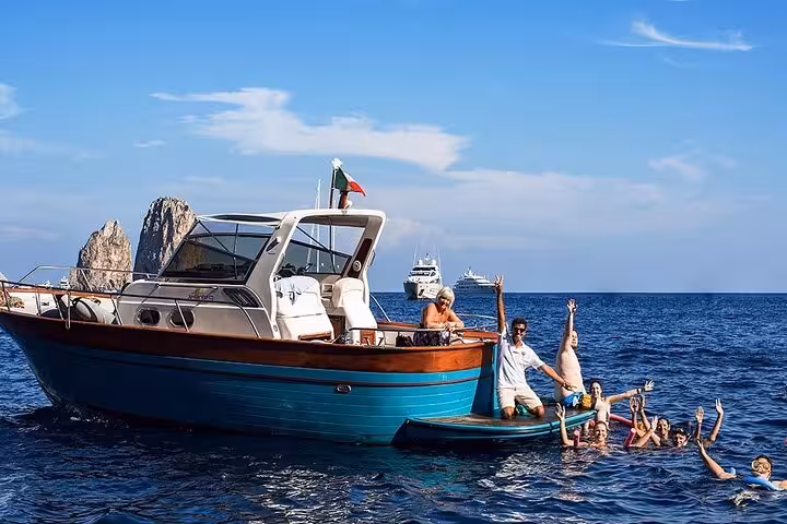 Group of friends swimming and enjoying a boat tour near the Faraglioni rocks on the Sorrento Coast.