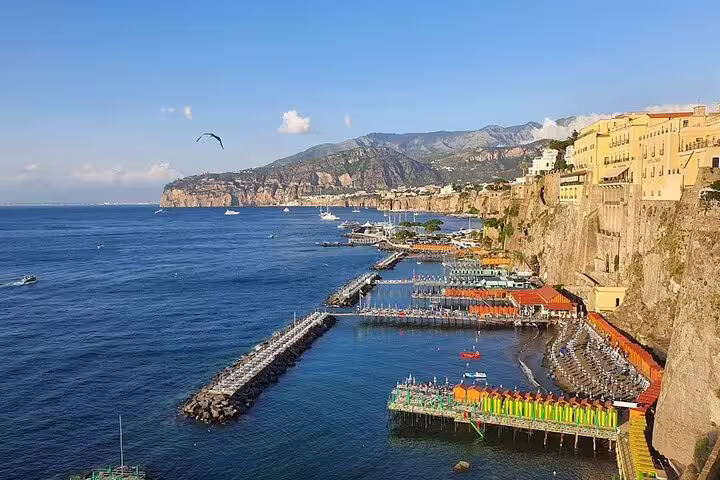Colorful marina and pier along dramatic cliffs of Sorrento coast with deep blue Mediterranean Sea