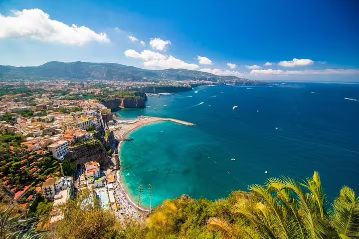Aerial view of Sorrento coastline with turquoise bay, cliffside buildings, and the Gulf of Naples, Italy