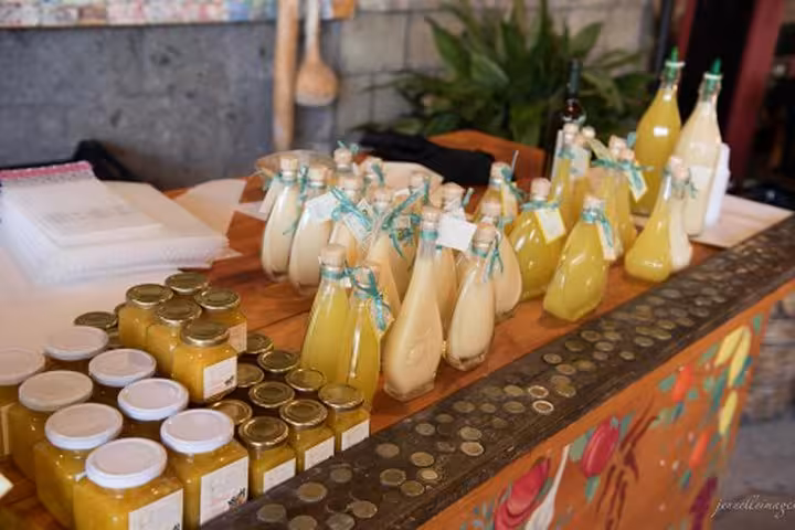 Assorted bottles of local lemon liqueurs and jars of preserves displayed on a colorful table, emphasizing Sorrento's culinary delights.