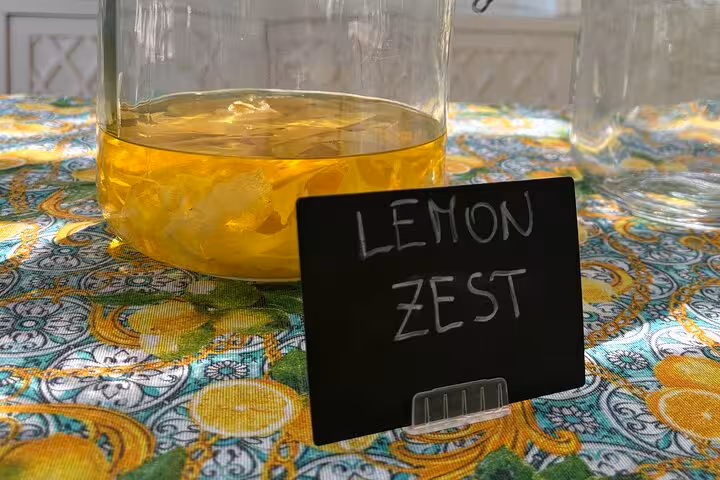 A jar of vibrant lemon zest infusion on a colorful lemon-patterned tablecloth, highlighting a Sorrento tasting experience.
