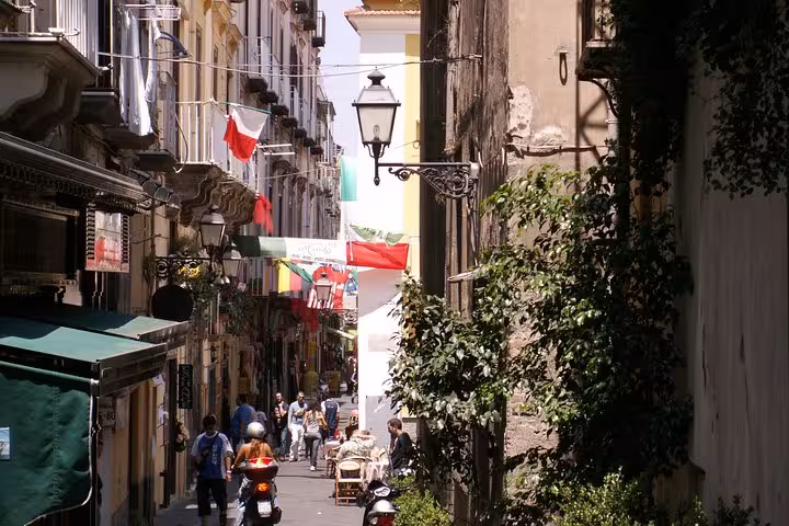 Charming street in Sorrento adorned with colorful flags and lively cafes, ideal for a Hercolaneum and Pompeii tour.