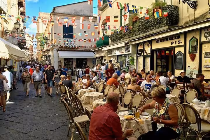 Bustling Sorrento street with outdoor cafes and colorful flags, capturing lively Italian culture.