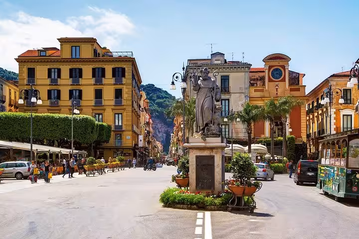 Stroll through the vibrant streets of Sorrento, featuring charming architecture and a central statue, on our guided day tour.