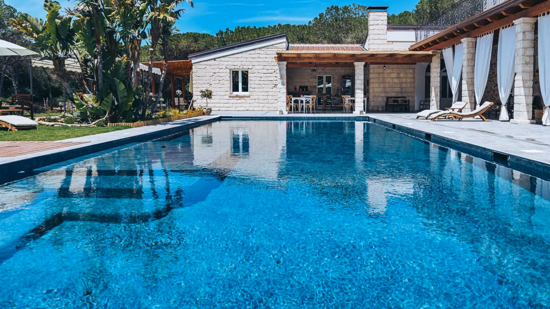 Luxurious villa pool with crystal-clear water and sun loungers, perfect for a relaxing getaway.