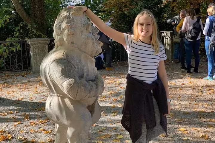 Girl touching a stone statue in Salzburg park on Sound of Music walking tour