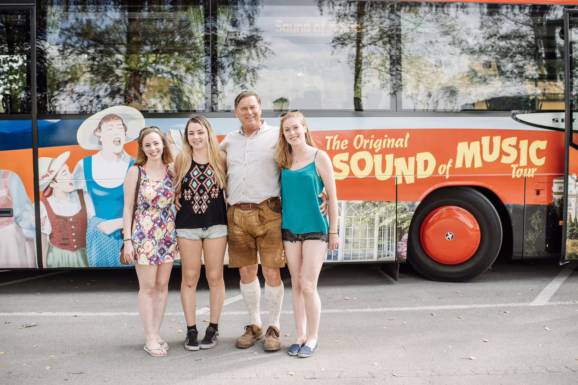 Visitors pose in front of the Sound of Music tour bus, showcasing vibrant images of the beloved musical in Salzburg.