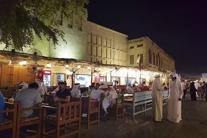 Outdoor dining at Souq Waqif, Doha, showcasing traditional Qatari ambiance with locals and tourists enjoying meals.