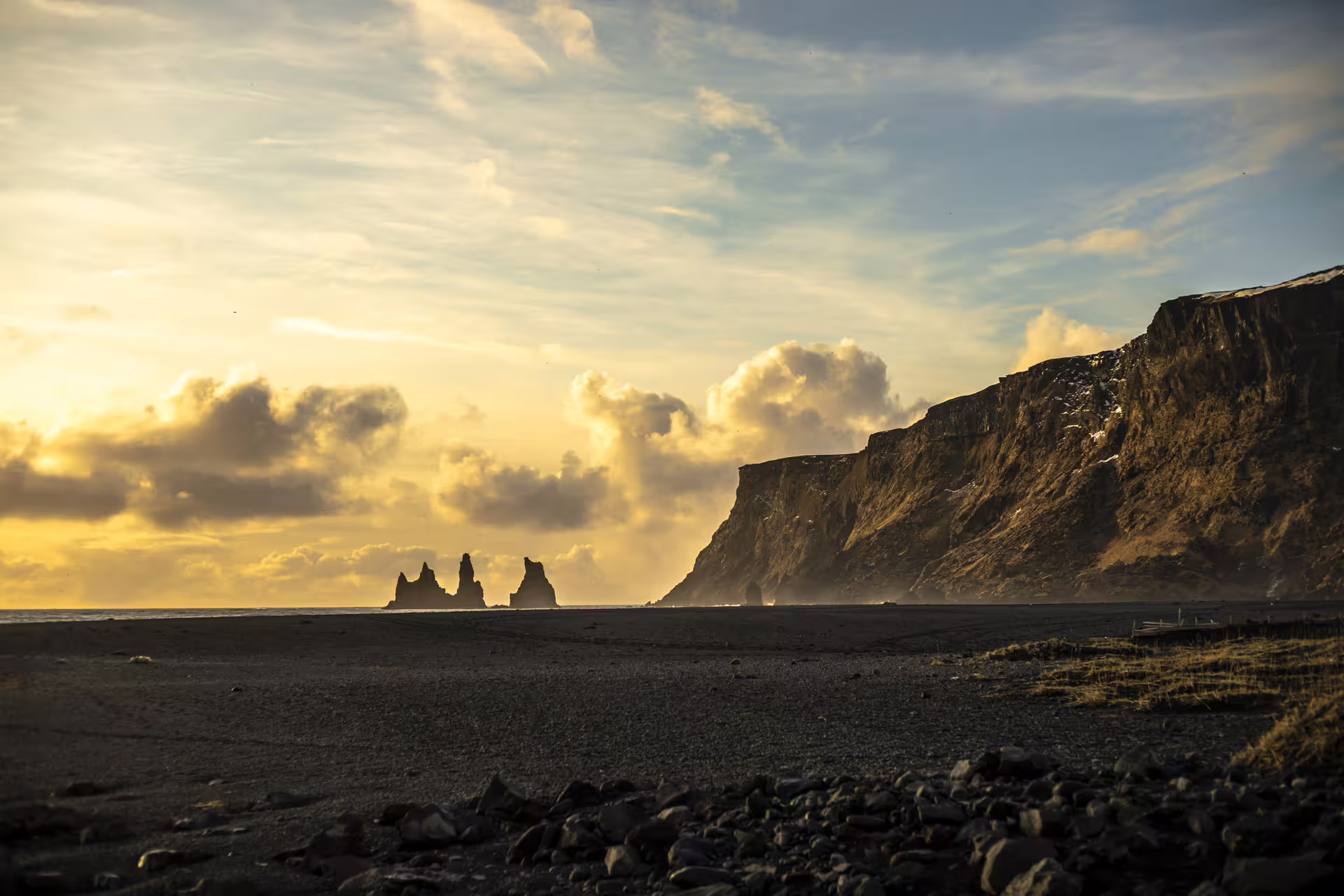Black sand beach at sunset with Reynisdrangar sea stacks and dramatic cliffs on Iceland's south coast