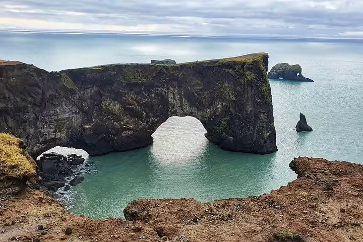 Dyrhólaey rock arch on Iceland's south coast with turquoise sea and dramatic black basalt cliffs