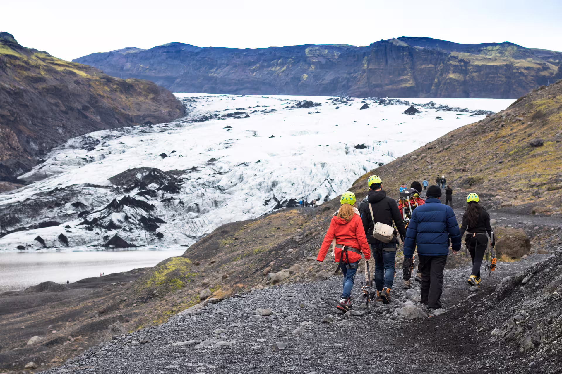 Hikers in helmets walking toward Sólheimajökull glacier on Iceland's south coast