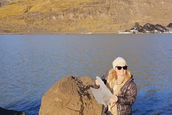 Woman holding ice chunk by glacial lake on Iceland's South Coast tour