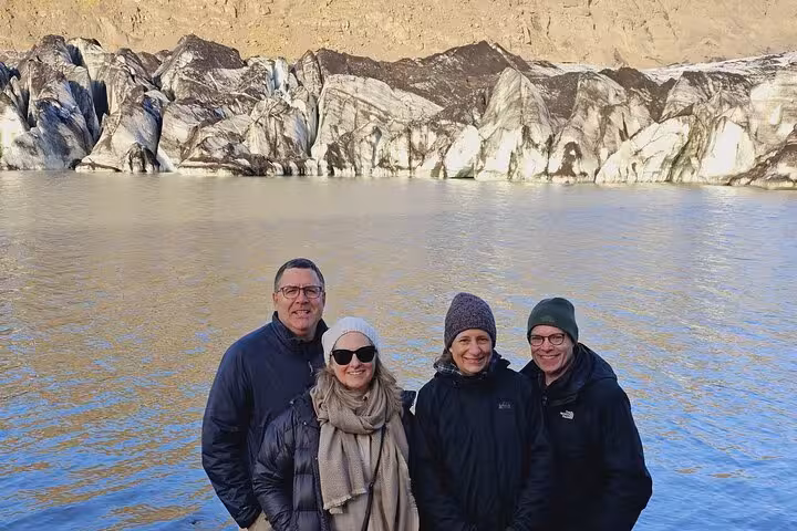 Four tourists posing in front of a glacier and glacial lagoon on Iceland's South Coast