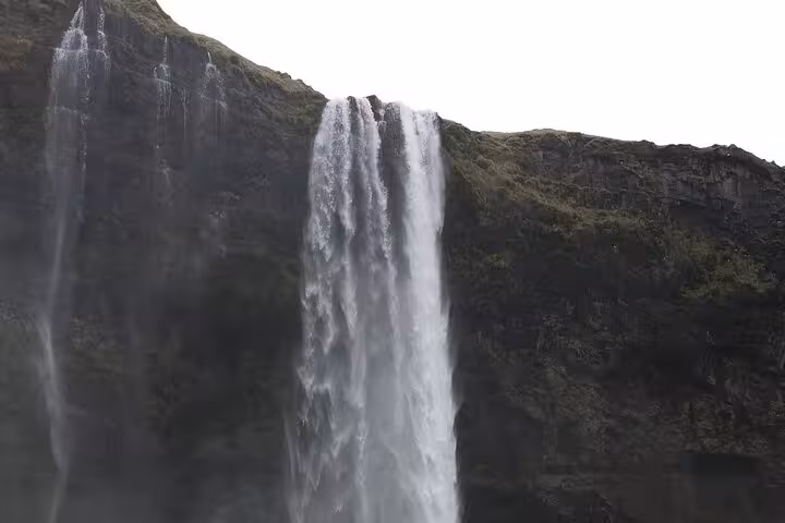 Powerful waterfall cascading down dark mossy cliffs on Iceland's South Coast