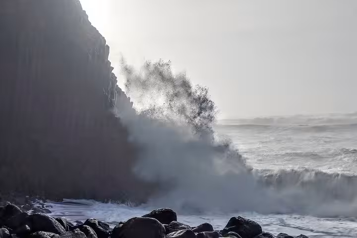 Massive waves crashing against dark basalt columns on Iceland's rugged south coast shoreline