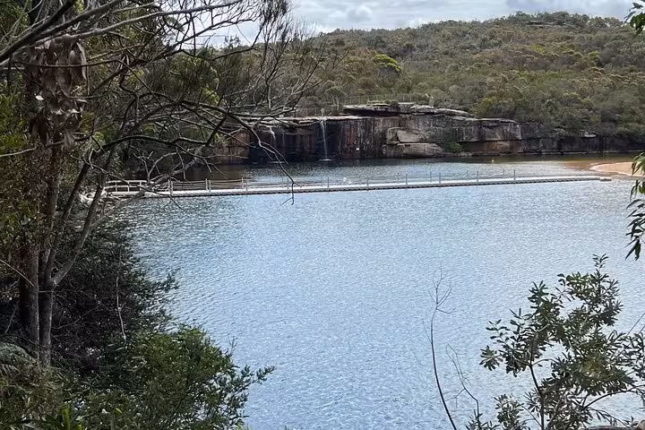 Scenic view of a tranquil lake with cascading waterfall and lush greenery on the South Coast private tour.
