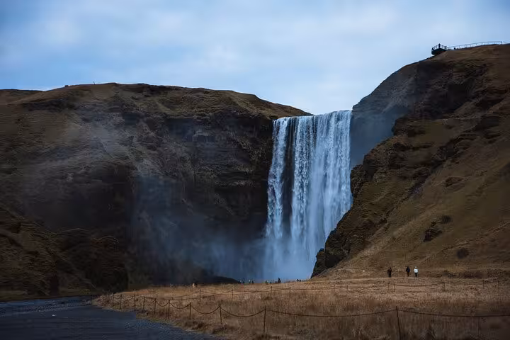 Skógafoss waterfall cascading down rocky cliffs on Iceland's South Coast with visitors below