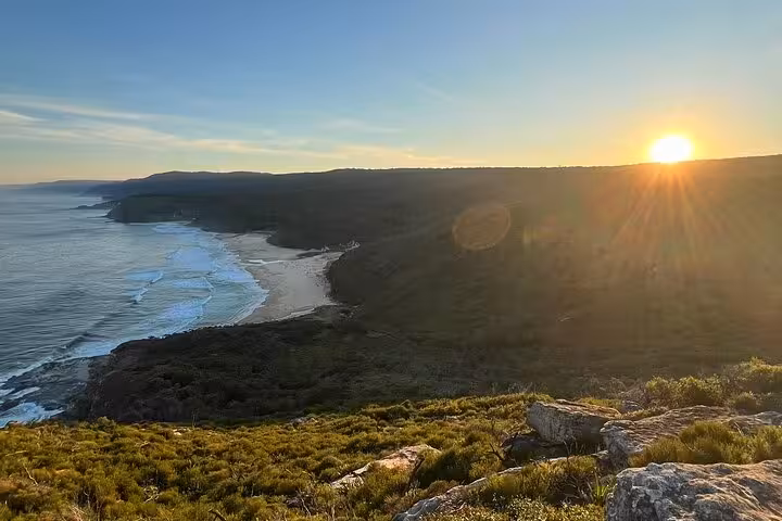 Breathtaking coastal sunset over rugged cliffs and crashing waves on the South Coast tour.