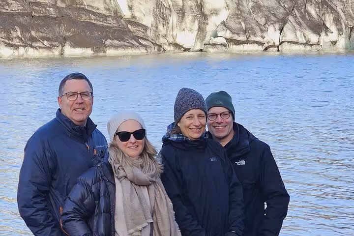 Four tourists posing together at black sand beach cliffs on South Coast tour from Reykjavik