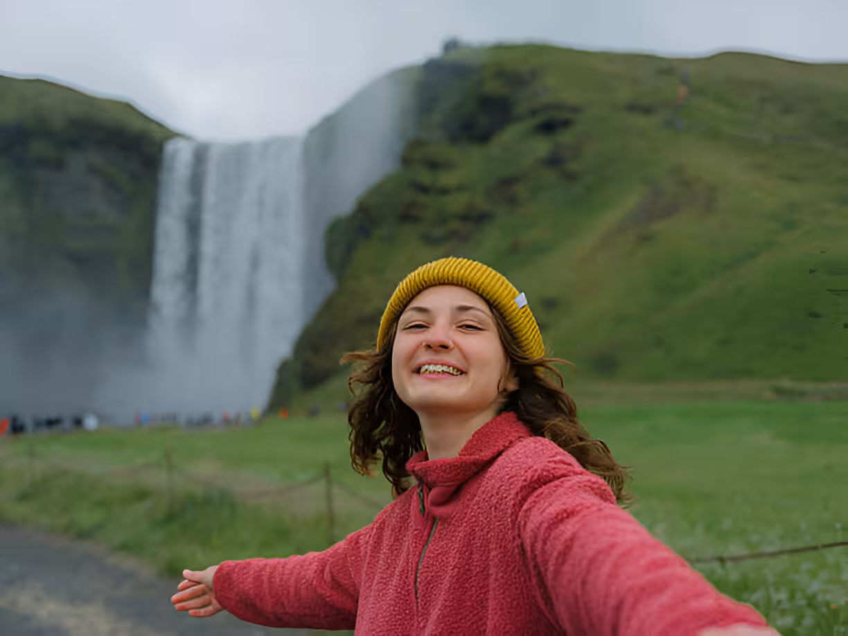 Happy traveler smiling at Skógafoss waterfall on Iceland's South Coast tour