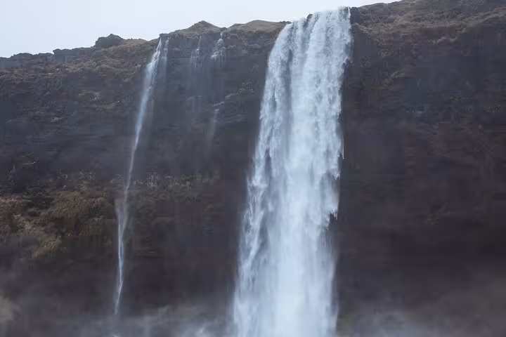 Powerful dual waterfalls cascading down a dark volcanic cliff face on Iceland's South Coast