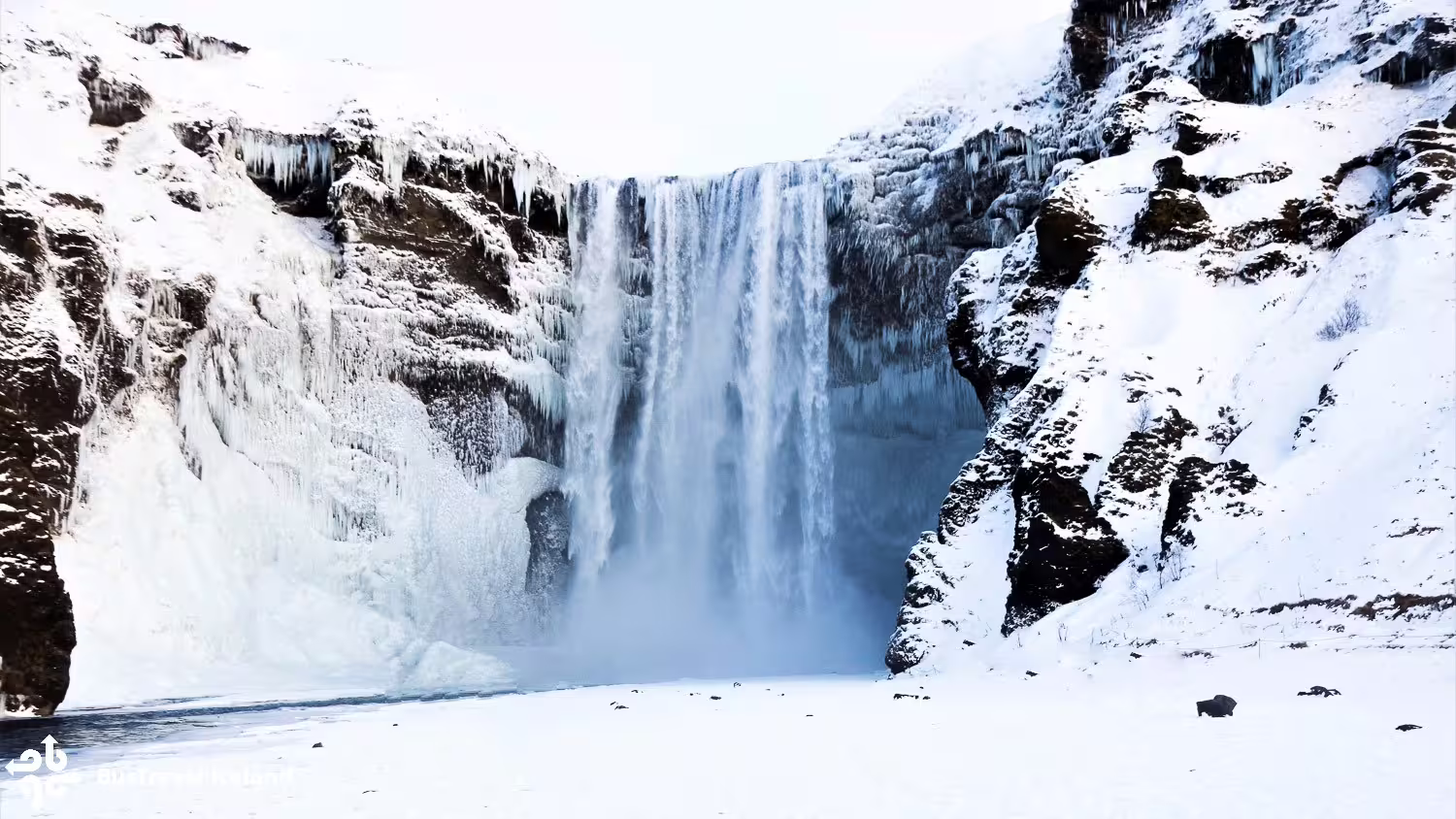 Skógafoss waterfall surrounded by snow and ice formations on Iceland's South Coast in winter