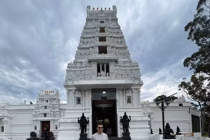 Stunning white temple facade with intricate carvings under a dramatic sky on the South Coast private tour.