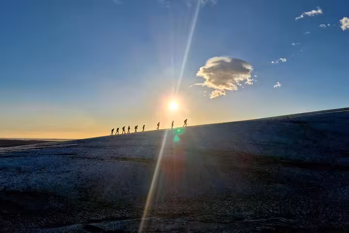 Silhouettes of hikers walking along a ridge at sunset during a South East Iceland photography tour