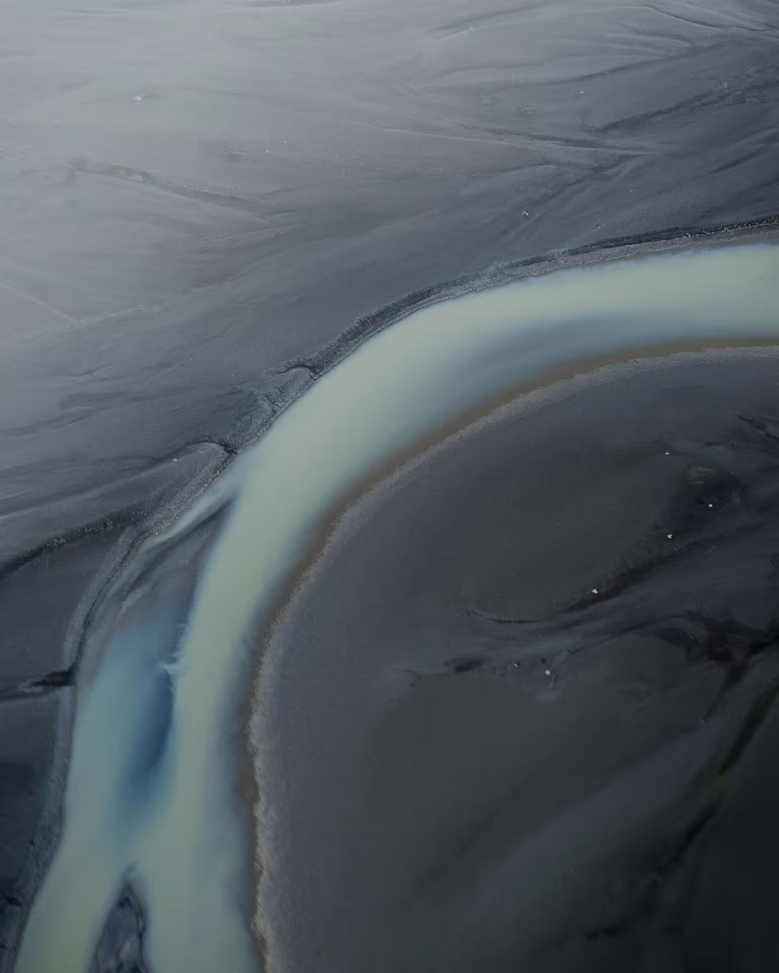 Aerial view of black sand and milky glacial river channels in South Iceland