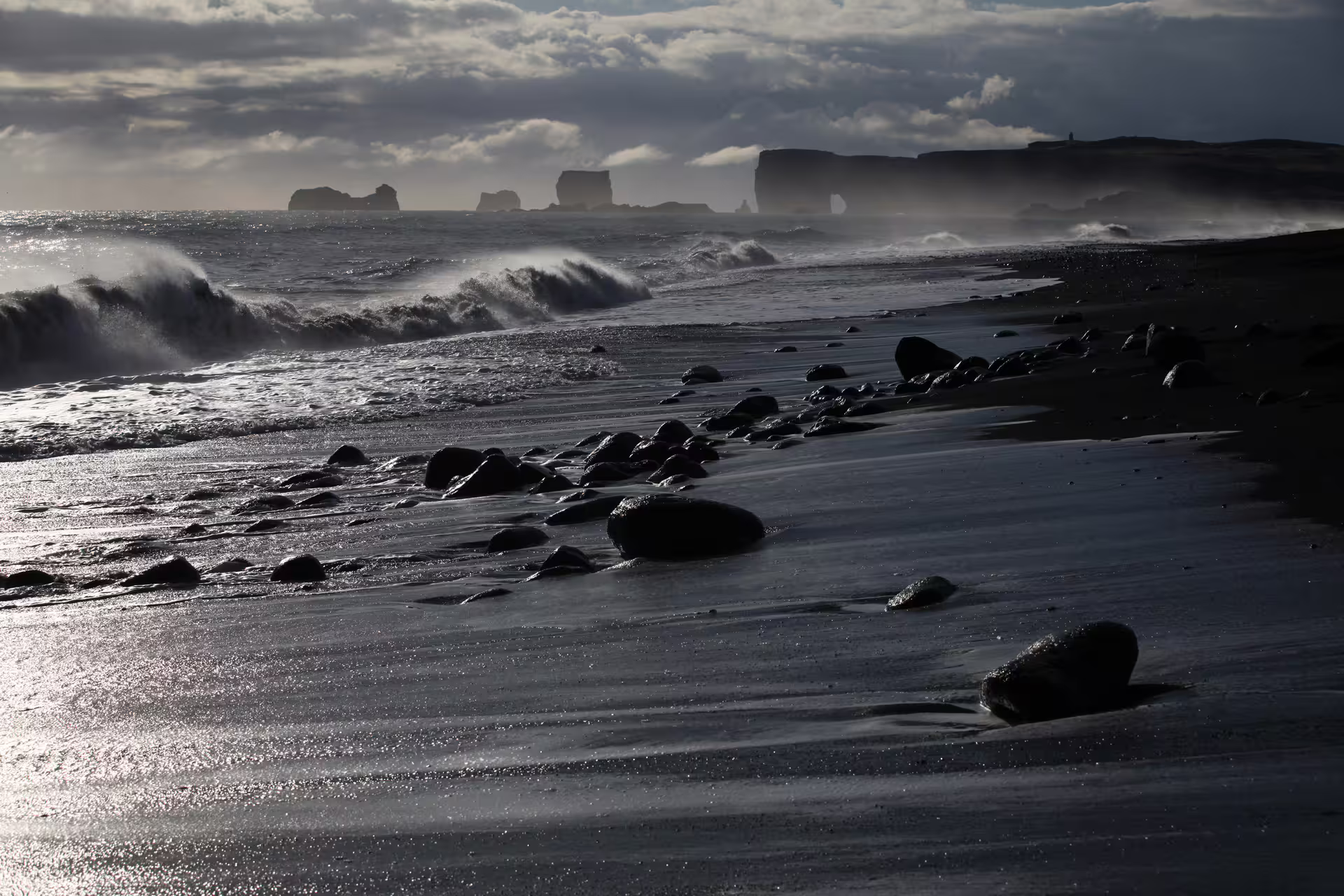 Black sand beach with volcanic rocks and crashing waves on Iceland's dramatic South Coast