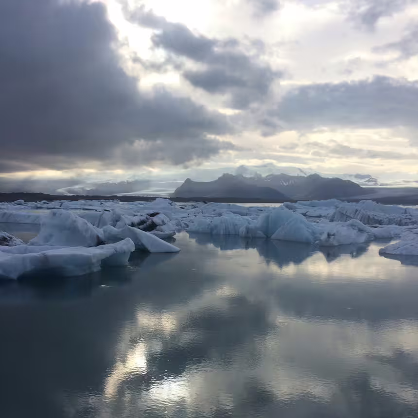 Icebergs floating on Jökulsárlón Glacier Lagoon with dramatic cloudy sky and mountains in South Iceland
