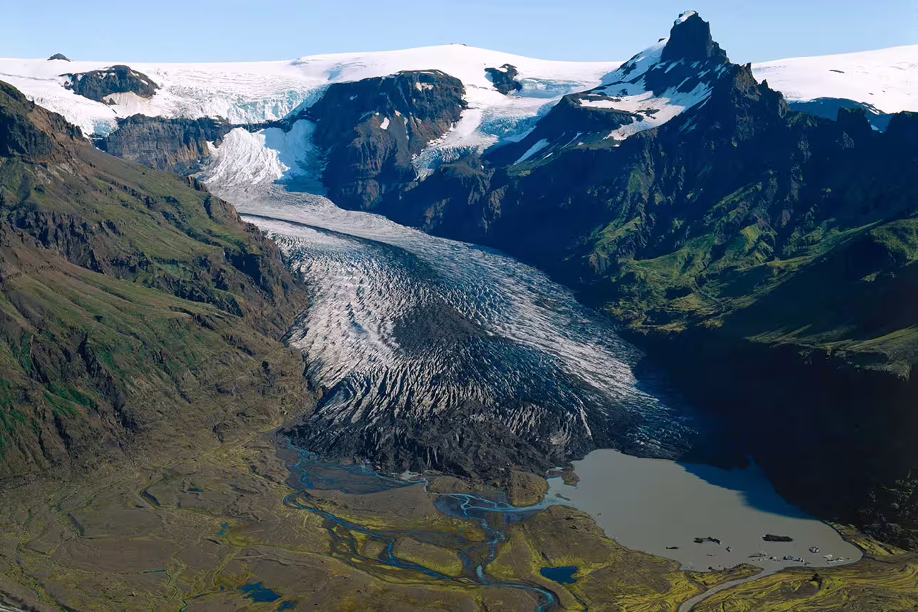 Aerial view of a glacier flowing through a mountain valley into a glacial lagoon in South Iceland