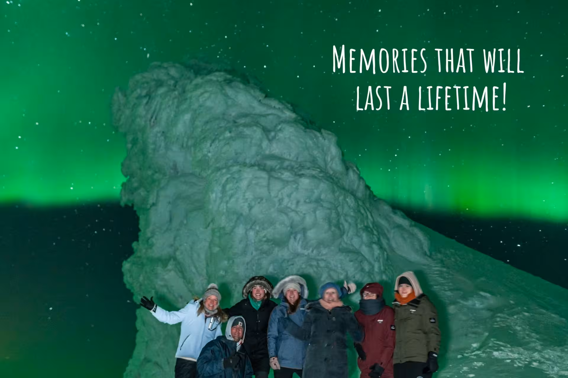 Group of travelers posing in front of snow formation under vibrant green northern lights in Iceland