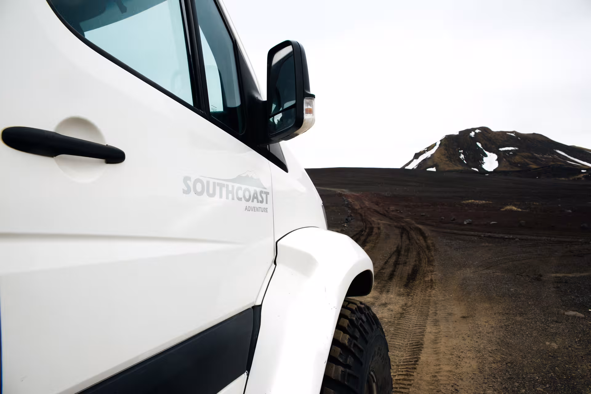South Coast Adventure super jeep on volcanic dirt track with snow-capped mountain in Iceland