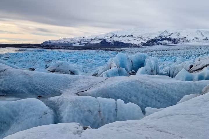 Vast blue glacier ice field with crevasses and snow-capped mountains in Southeast Iceland